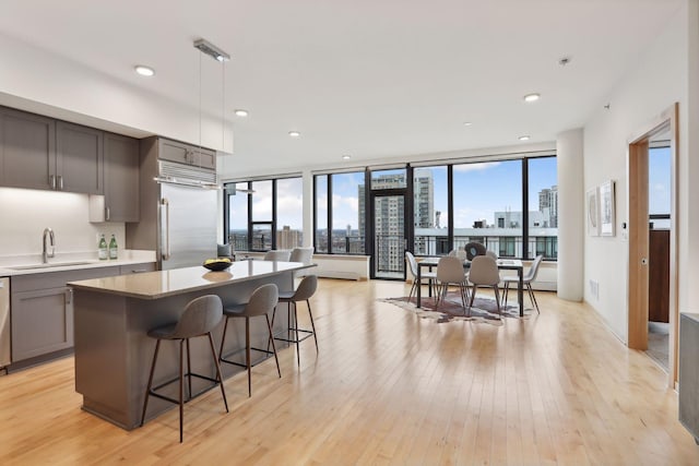 kitchen featuring sink, light stone counters, light hardwood / wood-style floors, pendant lighting, and appliances with stainless steel finishes