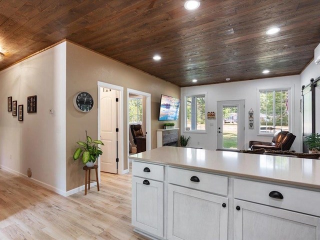 kitchen featuring white cabinetry, light hardwood / wood-style floors, wooden ceiling, and a barn door