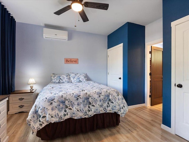 bedroom with an AC wall unit, light hardwood / wood-style floors, and ceiling fan