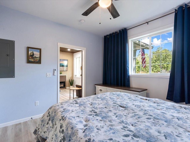 bedroom with ceiling fan, electric panel, and light wood-type flooring