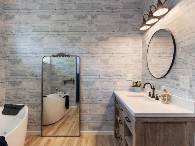 bathroom featuring vanity, wooden walls, a tub to relax in, and hardwood / wood-style floors