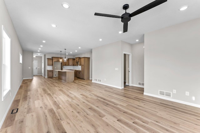 unfurnished living room with light wood-type flooring, ceiling fan, and sink