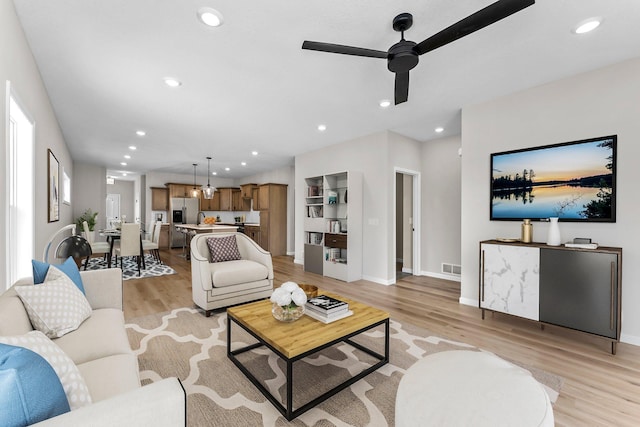 living room with ceiling fan and light hardwood / wood-style flooring