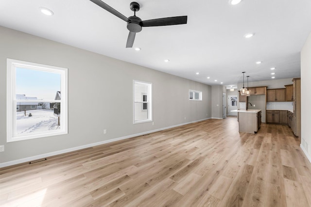 unfurnished living room featuring light hardwood / wood-style flooring, ceiling fan, and sink