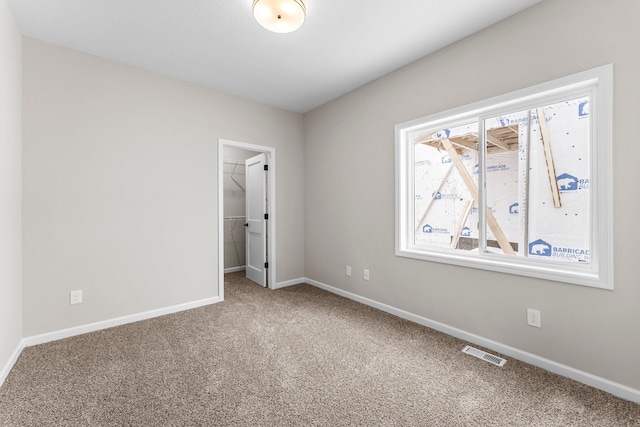 unfurnished bedroom with carpet flooring, a spacious closet, and a closet