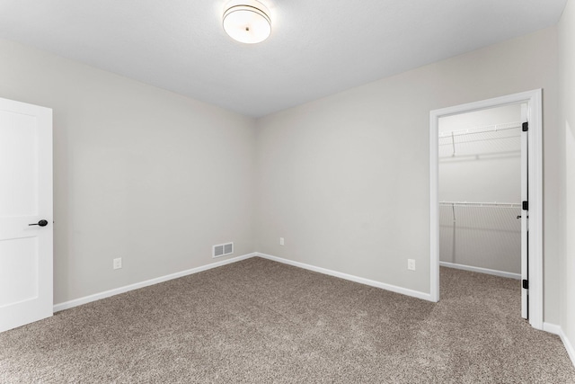 unfurnished bedroom with a walk in closet, carpet floors, and a closet