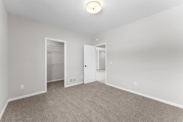 unfurnished bedroom featuring a walk in closet, a closet, and carpet