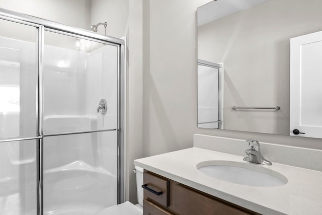 bathroom with an enclosed shower, vanity, and toilet