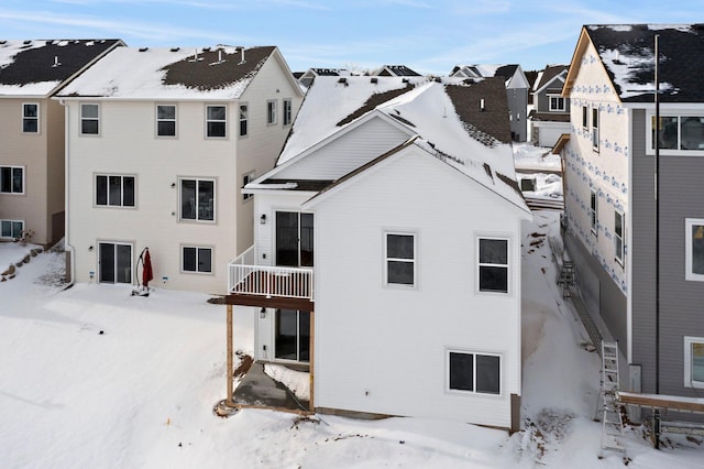 snow covered rear of property with a balcony