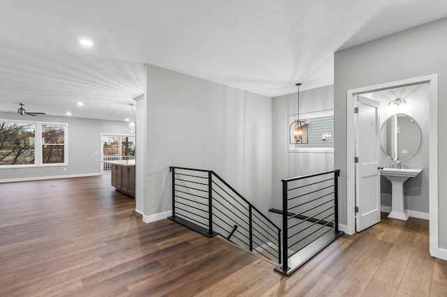 stairs with hardwood / wood-style floors, ceiling fan with notable chandelier, and a textured ceiling