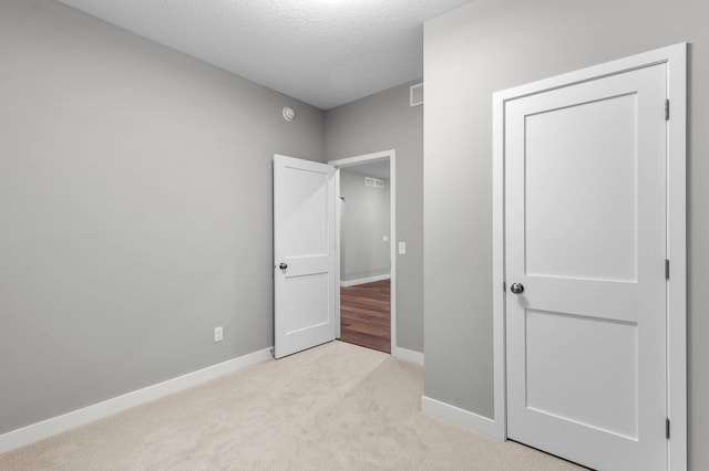 unfurnished bedroom with light colored carpet and a textured ceiling