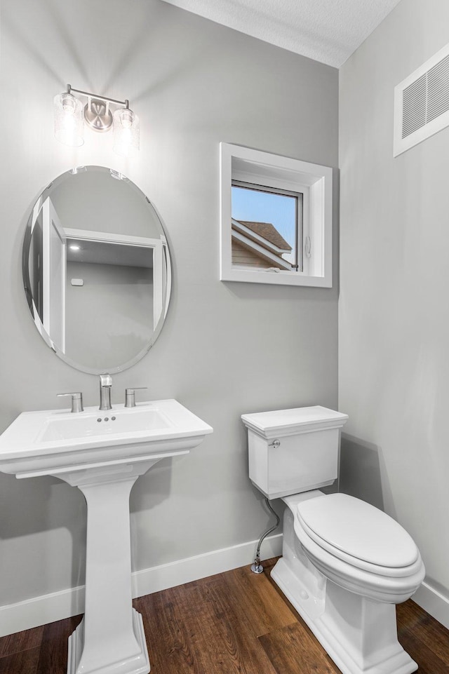 bathroom with hardwood / wood-style flooring, toilet, sink, and a textured ceiling