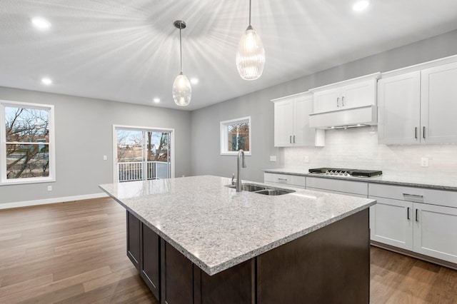 kitchen with light stone countertops, pendant lighting, white cabinetry, and sink