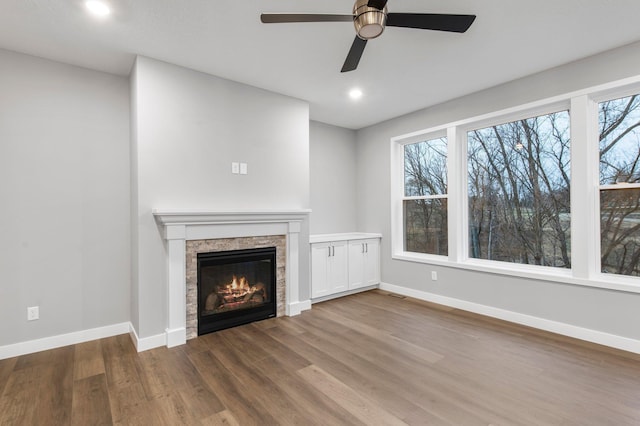 unfurnished living room featuring ceiling fan, plenty of natural light, and wood-type flooring