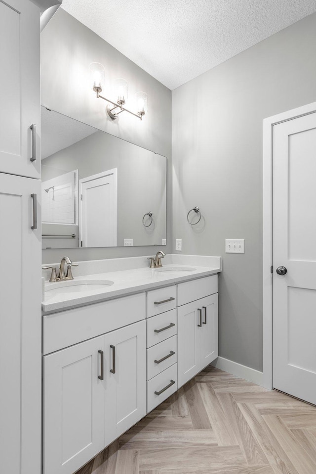 bathroom featuring parquet flooring, vanity, and a textured ceiling