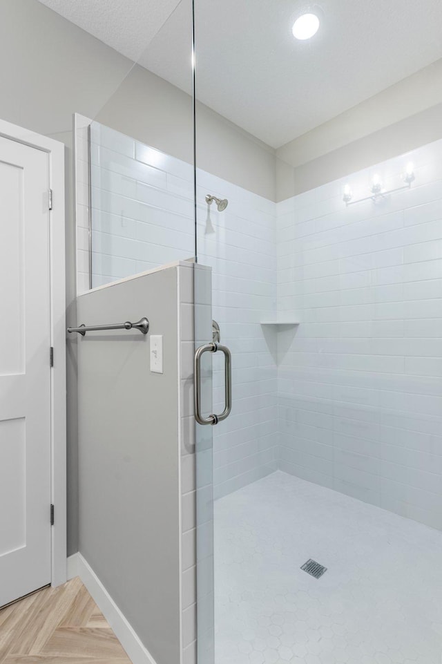 bathroom with a shower with shower door and parquet floors