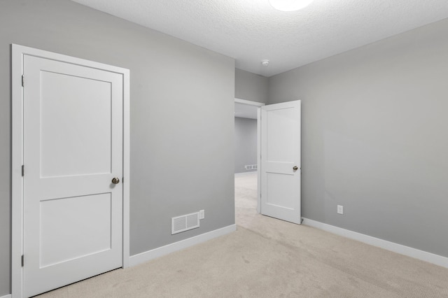 unfurnished bedroom with light carpet and a textured ceiling