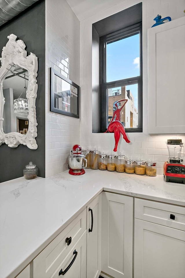 interior space with decorative backsplash, white cabinetry, and light stone counters