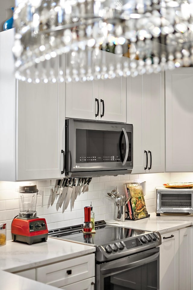 kitchen with appliances with stainless steel finishes, decorative backsplash, white cabinetry, and light stone counters