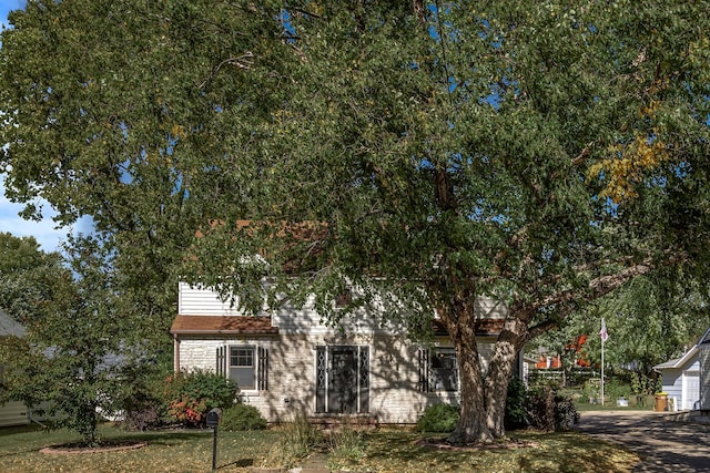 obstructed view of property with a front lawn