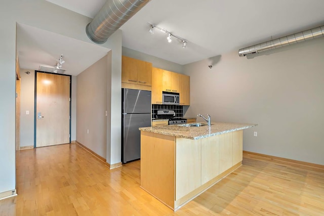 kitchen featuring tasteful backsplash, sink, light hardwood / wood-style floors, stainless steel appliances, and light stone countertops