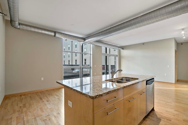 kitchen featuring sink, light stone counters, a center island with sink, dishwasher, and light hardwood / wood-style floors