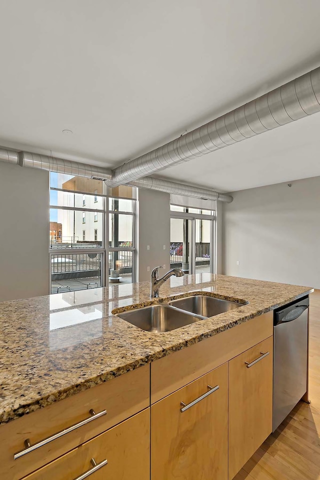 kitchen featuring light brown cabinetry, sink, light stone counters, light hardwood / wood-style flooring, and dishwasher