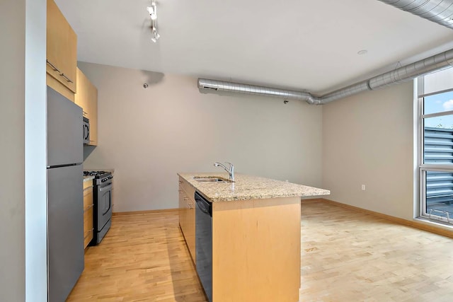 kitchen with light brown cabinetry, sink, an island with sink, stainless steel appliances, and light hardwood / wood-style floors