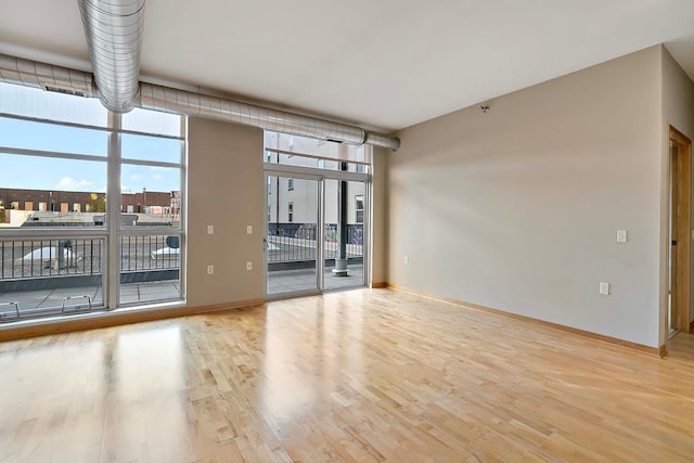 unfurnished room with light hardwood / wood-style floors and expansive windows