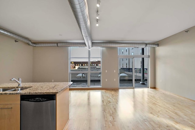 interior space with sink, light wood-type flooring, stainless steel dishwasher, a wall of windows, and light stone countertops