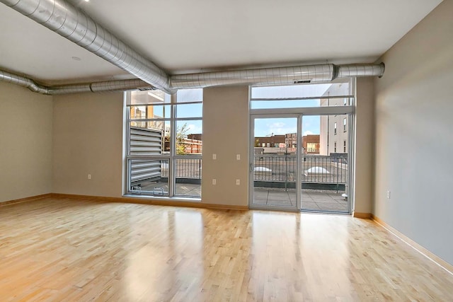 spare room featuring floor to ceiling windows and light hardwood / wood-style floors