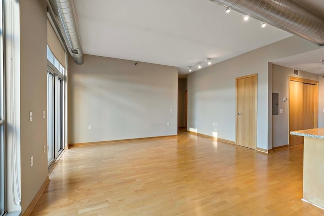 empty room featuring electric panel and light wood-type flooring