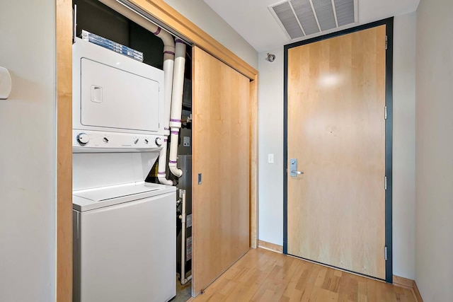 washroom with stacked washer and clothes dryer and light hardwood / wood-style flooring