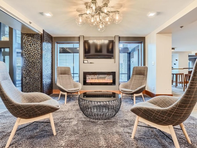 sitting room with a chandelier, a glass covered fireplace, and baseboards