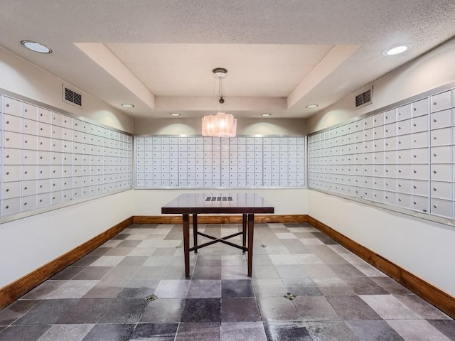 interior space with a raised ceiling, visible vents, and baseboards