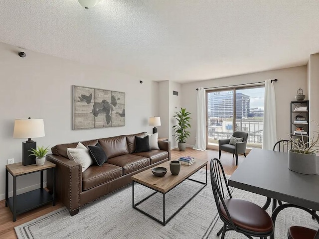 living room featuring a textured ceiling, light wood-style flooring, and baseboards