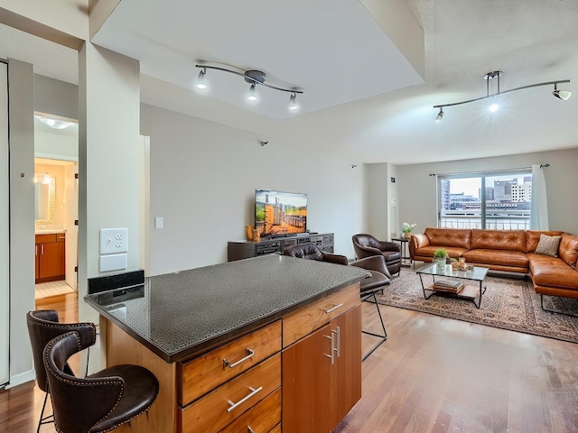 kitchen featuring dark countertops, a kitchen breakfast bar, wood finished floors, and open floor plan