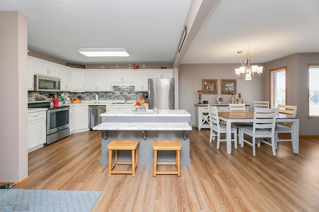 kitchen with light hardwood / wood-style floors, stainless steel appliances, sink, and white cabinetry