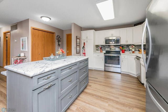 kitchen with gray cabinets, white cabinetry, and appliances with stainless steel finishes