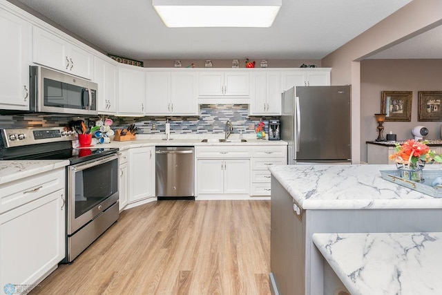 kitchen with light wood-type flooring, white cabinetry, sink, and stainless steel appliances