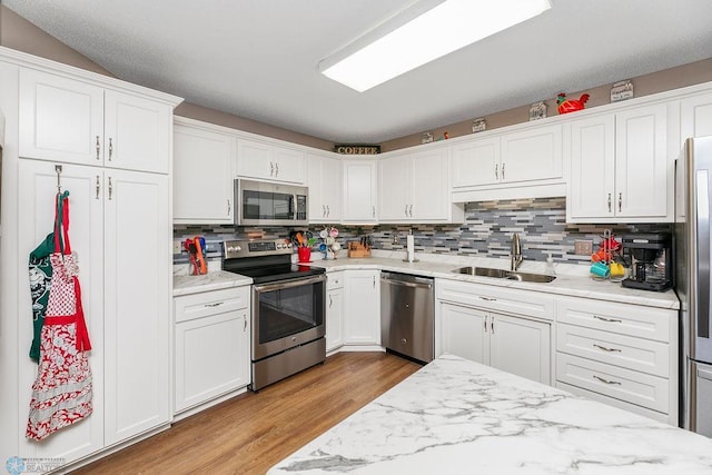 kitchen featuring light hardwood / wood-style floors, stainless steel appliances, sink, and white cabinetry