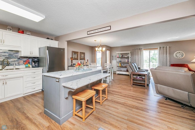 kitchen featuring a notable chandelier, white cabinetry, a breakfast bar, and stainless steel fridge