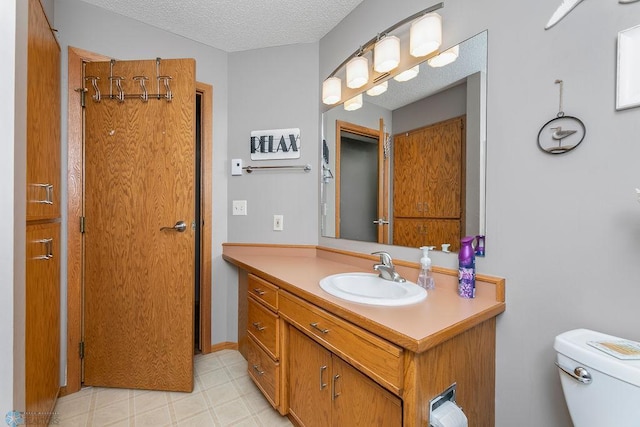 bathroom with a textured ceiling, vanity, and toilet