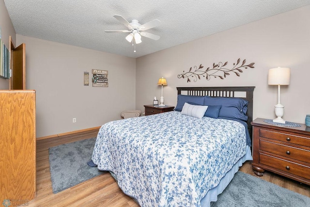 bedroom with ceiling fan, hardwood / wood-style floors, and a textured ceiling