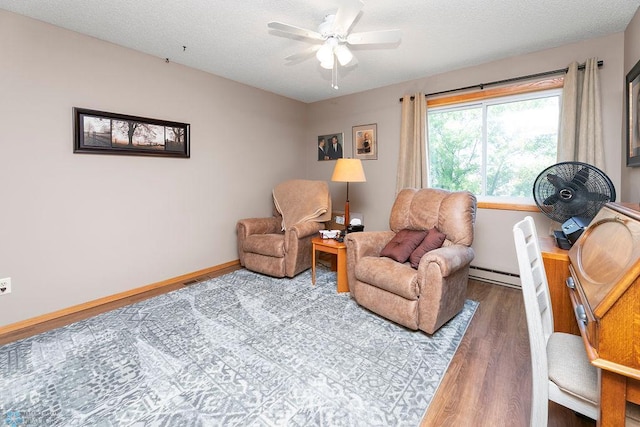 living area featuring ceiling fan, a textured ceiling, hardwood / wood-style floors, and a baseboard heating unit