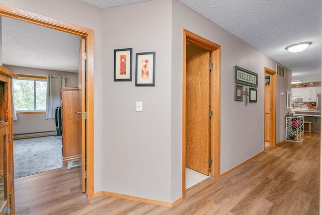 hall featuring a textured ceiling, light hardwood / wood-style floors, and a baseboard radiator