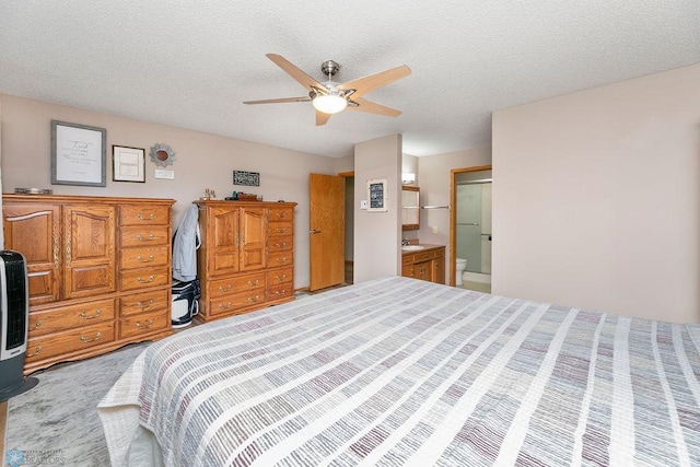 bedroom with ensuite bath, ceiling fan, sink, and a textured ceiling