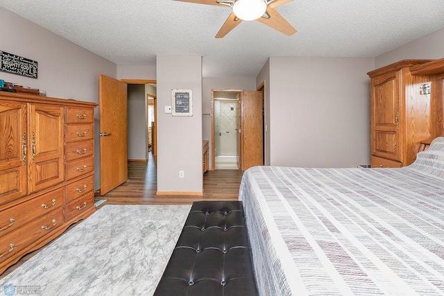 bedroom with light wood-type flooring, ensuite bath, ceiling fan, and a textured ceiling