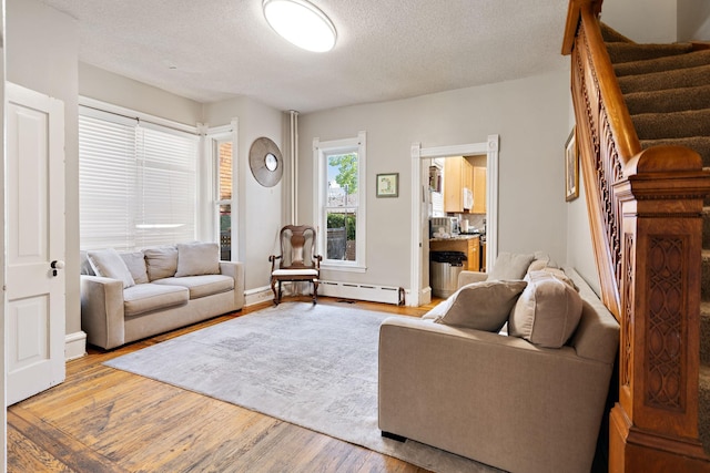 living room with a baseboard heating unit, a textured ceiling, and hardwood / wood-style flooring