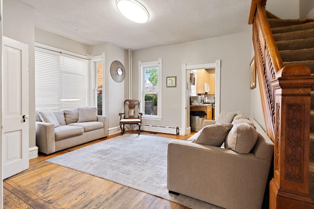 3017 James Ave S, Minneapolis, MN 55408 - living room with stairs, wood finished floors, a textured ceiling, and baseboard heating